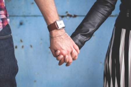 2 Person Holding Hands Besides Blue Painted Wall photo