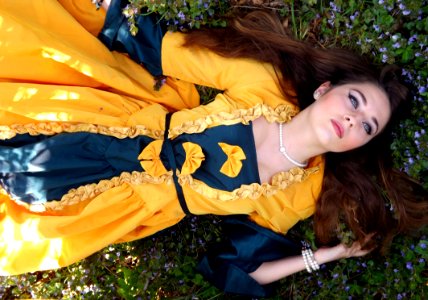 Woman In Yellow And Blue Dress Lying On A Grass Field