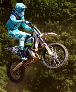 Man In Blue Mtx Suit Riding Blue And Yellow Dirt Motorcycle In Air