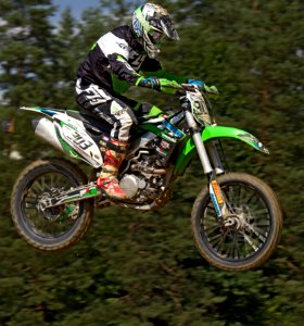 Man In Green White And Black Mtx Suit On Green And White 303 Dirt Motorcycle In The Air