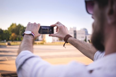 Tilt Shift Photo Of Man Holding Black Smartphone Taking Photo Of Gray Ground At Daytime photo