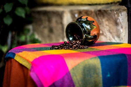 Brown And Black Ceramic Coffee Bean Rack On Pink Green And Yellow Textile