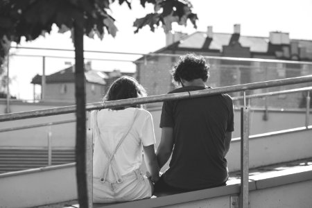 Grayscale Photo Of Man And Woman Sitting On Inclined Road photo