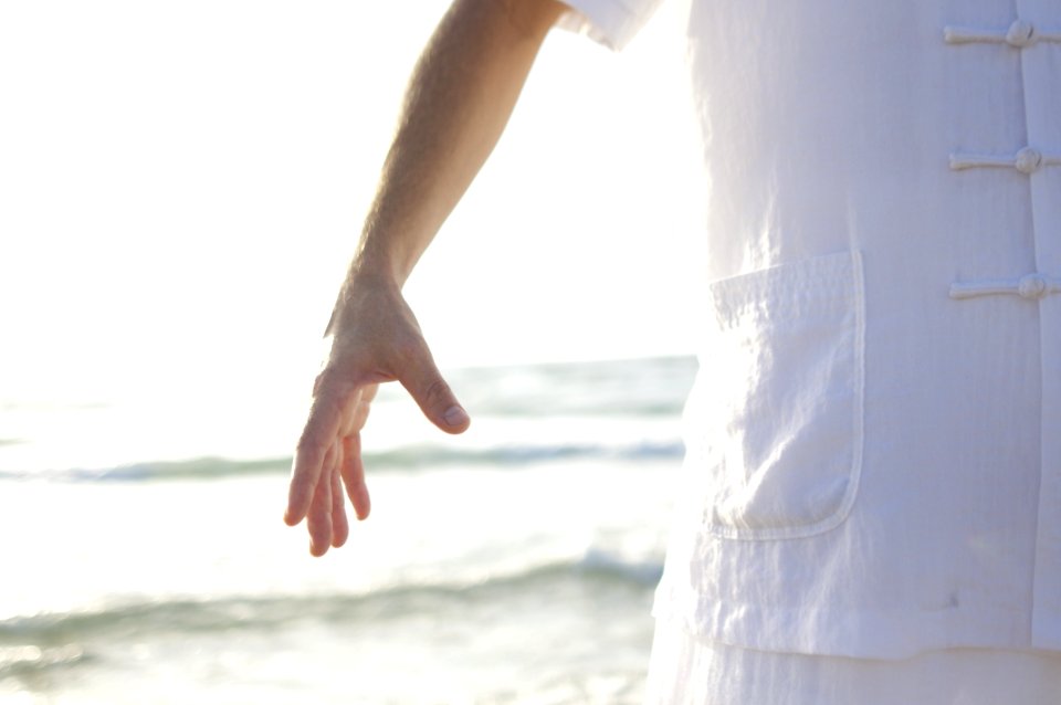 Person In White Shirt Standing On Seashore During Daytime photo