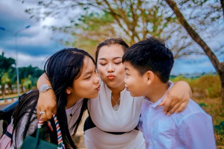 Three Person Kissing Near Tree photo