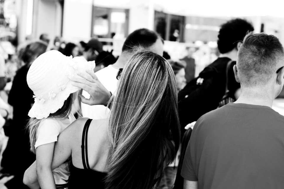 Woman Carrying A Child Wearing A Sun Hat Standing Next To A Man photo