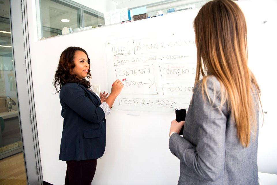 Woman In Black Blazer Looking At Woman In Grey Blazer