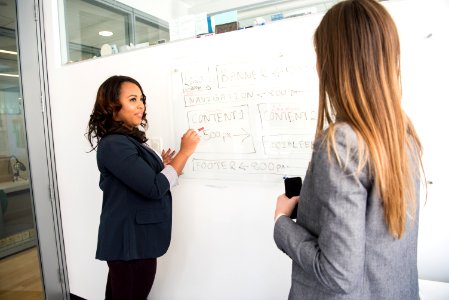 Woman In Black Blazer Looking At Woman In Grey Blazer
