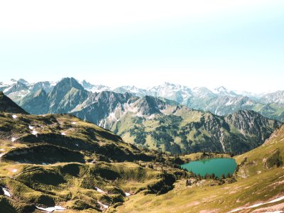 Beige And Green Mountain With Teal Lake Under White Sky At Daytime