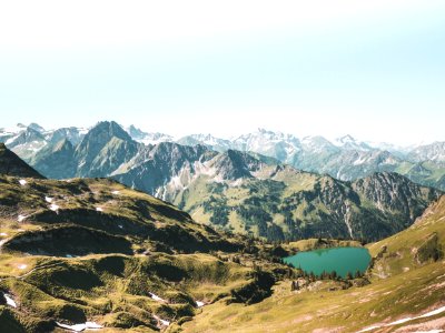 Beige And Green Mountain With Teal Lake Under White Sky At Daytime photo