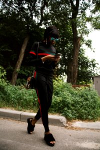 Woman In Black Green And Red Gucci Sweatshirt And Sweatpants Using Smartphone