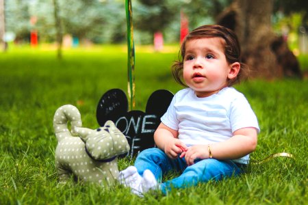 Depth Of Field Photography Of Baby Sitting On Green Grass