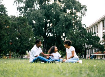 Family Sitting On Grass Near Building photo