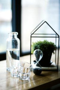 Shot Glasses And Hourglass On Brown Wooden Surface photo