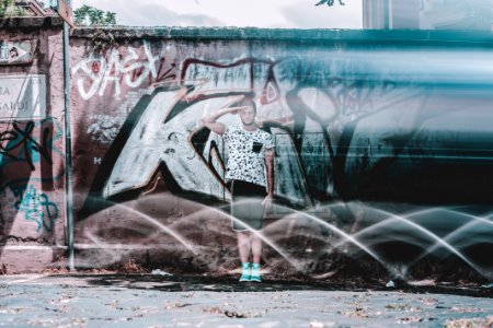 Man In White Shirt And Black Shorts Saluting Graffiti At Daytime photo