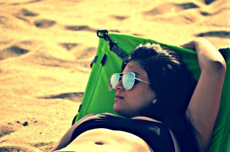 Woman Wearing Bikini Top Lying On Bed Beside Sand At Daytime photo