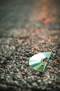 Selective Focus Photography Of Half Cut Compact Disc On Gray Pavement photo