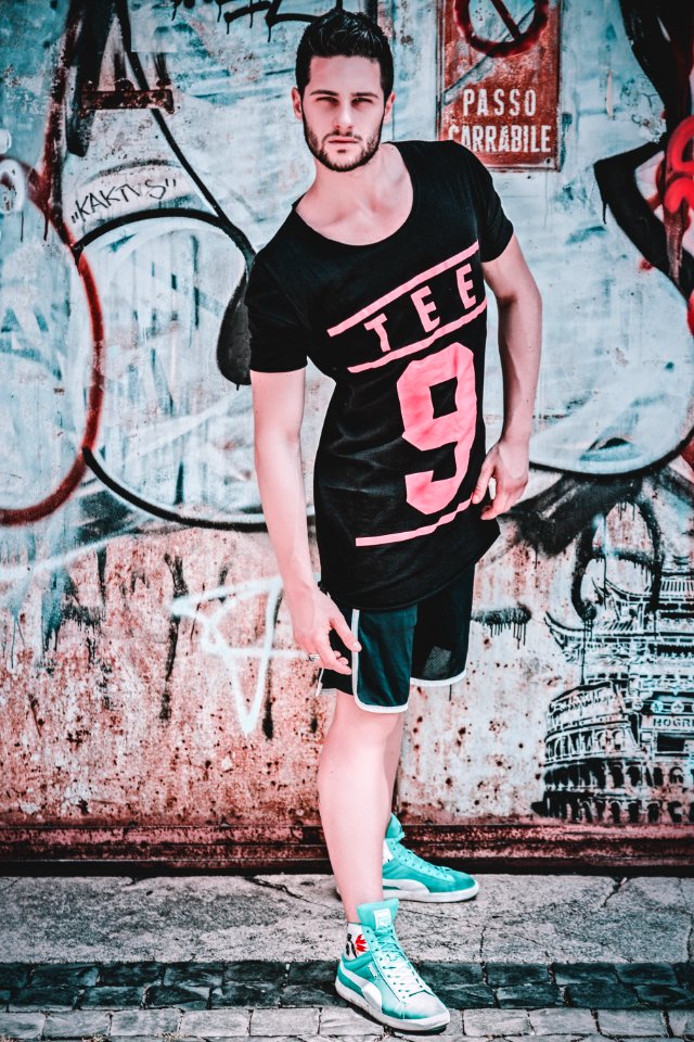 Man Wearing Black And Pink Tee 9-printed T-shirt In Front Of Wall