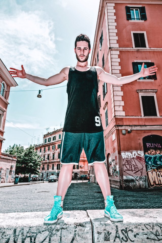 Man In Black Tank Top And Green Shorts Posing Near Building