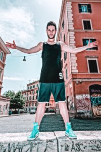 Man In Black Tank Top And Green Shorts Posing Near Building photo