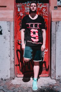 Photo Of Man Leaning On Red Metal Door photo