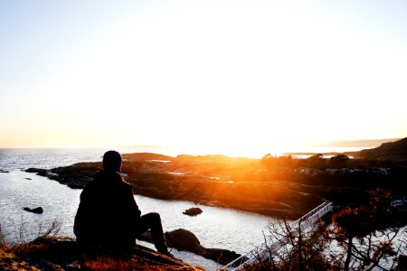Silhouette Photo Of Person Sitting Near Cliff During Golden Hour photo