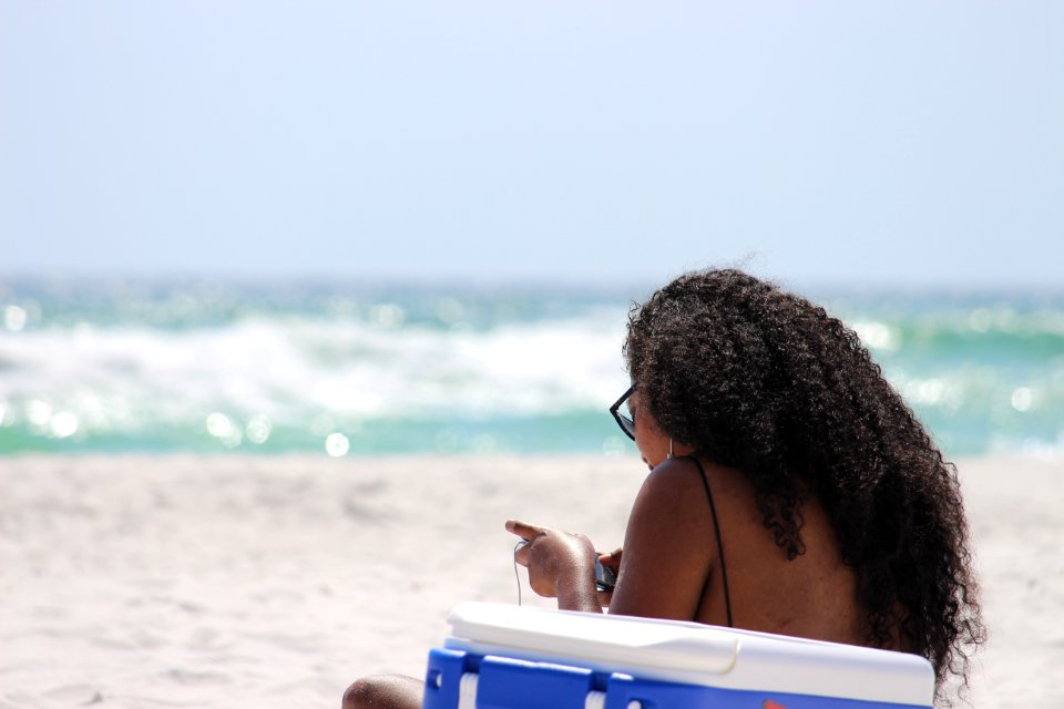 Woman Sitting On Sand Beside Blue And White Cooler Box Near Shore