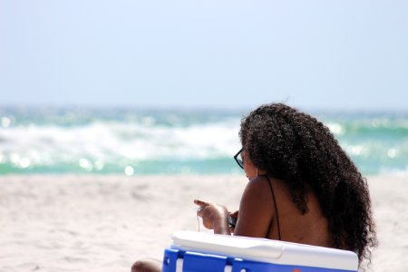 Woman Sitting On Sand Beside Blue And White Cooler Box Near Shore photo