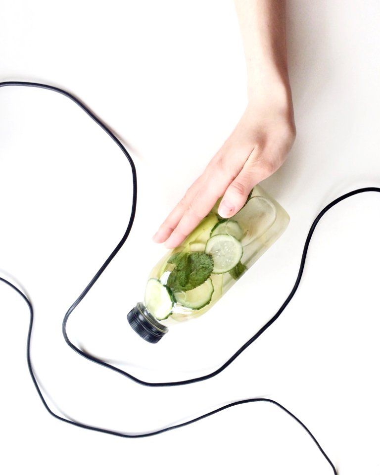 Person Holding Bottle And Cucumber