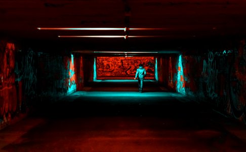 Person Wearing Jacket Walking On Tunnel With Red And Green Lights photo