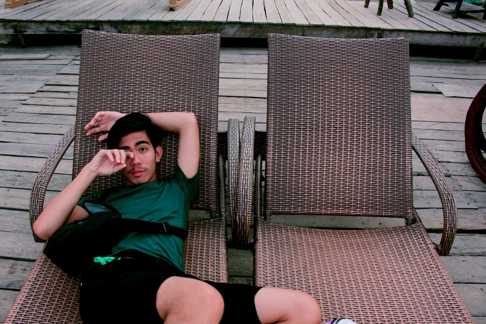 Man Wearing Green Shirt And Black Shorts Laying On Lounger