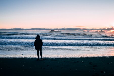 Person Standing On Beach Seashore During Sunset photo