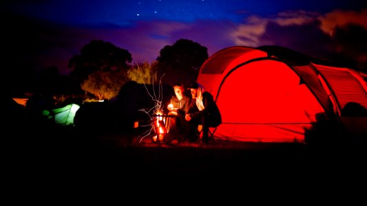 Man And Woman Sitting Beside Bonfire During Nigh Time