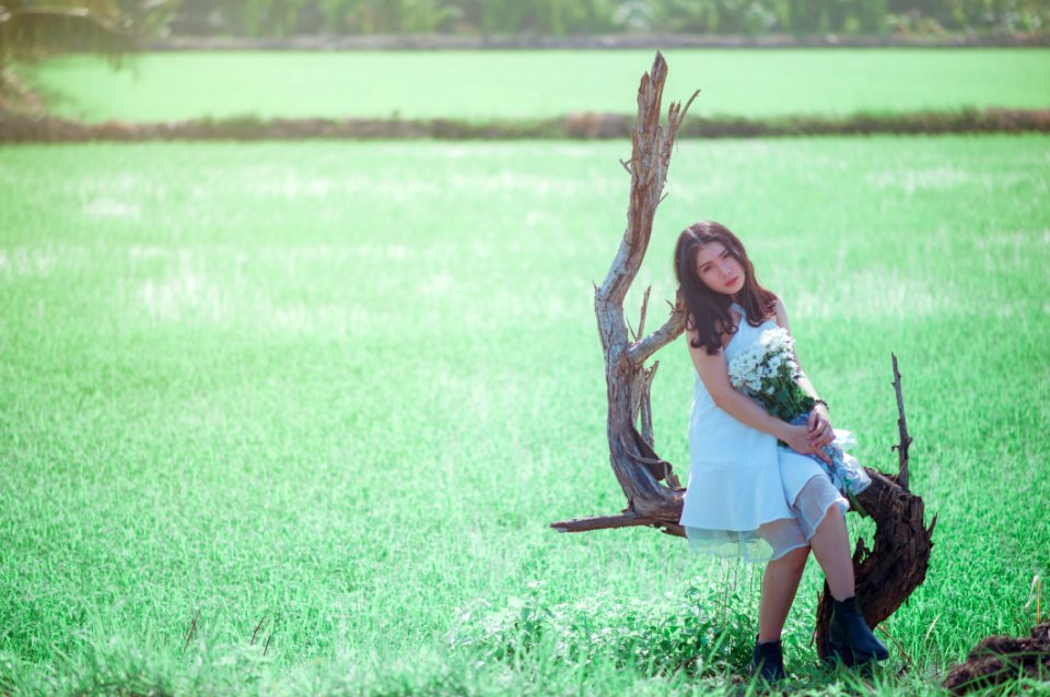 Woman Sitting On Tree While Holding Bouquet Of White Flower