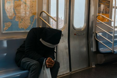 Person In Black Hoodie Sitting On Train Bench photo
