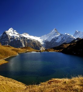 Sunlit Lake Close To Snow Covered Mountains