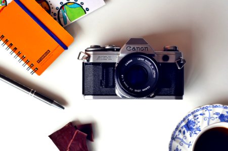 Gray And Black Canon Mirrorless Camera Beside Blue And White Ceramic Plate