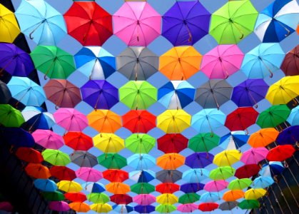 Yellow Blue Red Pink Purple Green Multicolored Open Umbrellas Hanging On Strings Under Blue Sky photo