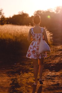 Woman In White And Pink Floral Sleeveless Dress Walking On Brown Road During Sunlight photo