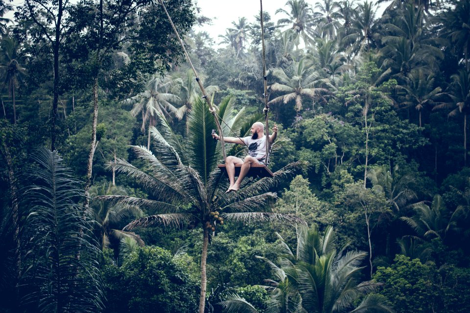BALI INDONESIA - DECEMBER 26 2017 Man Having Fun On The Swing With Action Camera In The Jungle Of Bali Island Indonesia Rainf