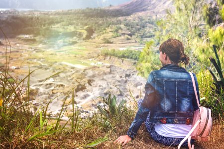 Young Woman Sitting On A Rock With Backpack And Looking To The Horizon Bali Island Volcano Batur