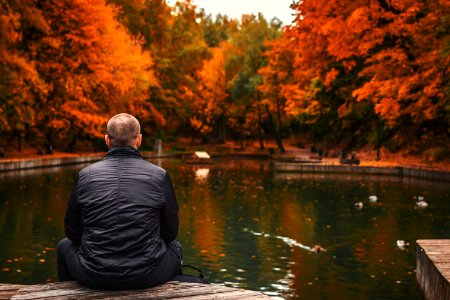 Alone Man Sits Beside A Pond In The Park Autumn Background photo