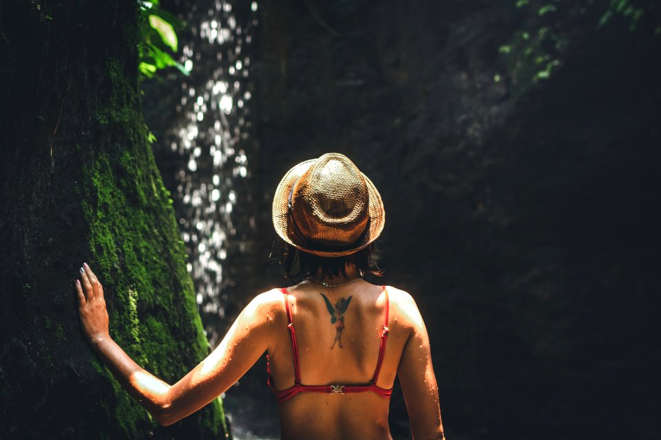 Young Woman Tourist With Straw Hat Deep In The Rainforest With Waterfall Background Bali Island