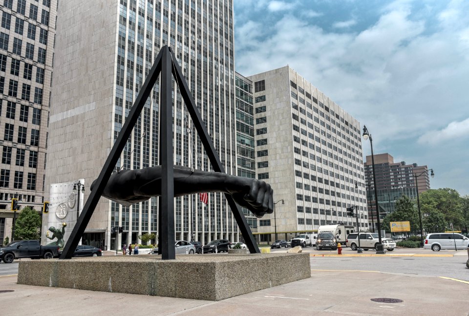 Statue Of Human Arm Near Gray Buildings