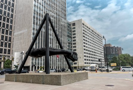 Statue Of Human Arm Near Gray Buildings