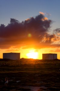 The sun sets between two fuel tanks