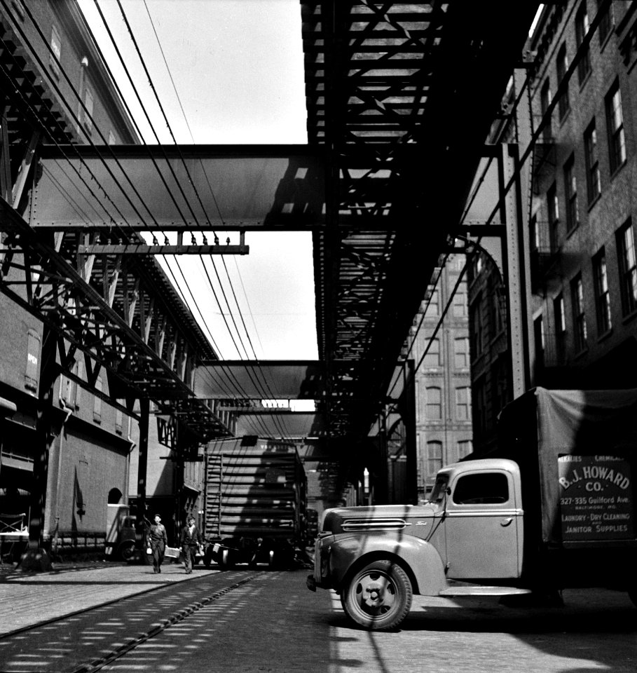 Trucks and trains unloading goods underneath an elevated trolley. Baltimore, Maryland. April 1943.
