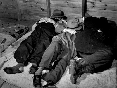 Flop House: Impoverished farmers sleeping in a white camp room in a warehouse. They often must remain several days before their tobacco is sold. Durham, North Carolina, 1939.