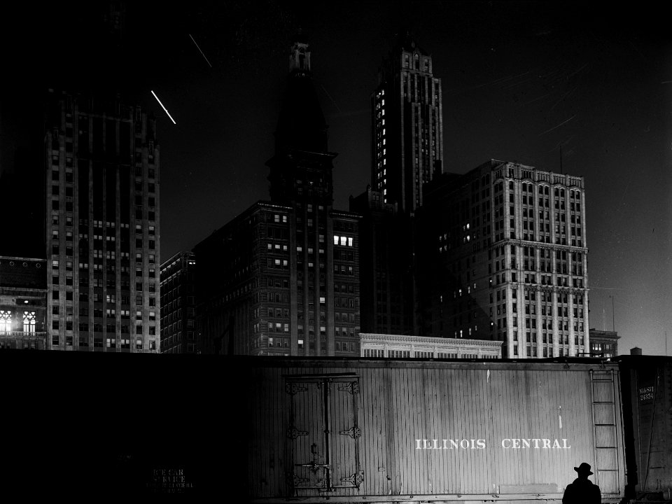 Chicago Noir: Special agent making his rounds at night at the South Water Street freight terminal of the Illinois Central Railroad. Chicago, Illinois. May 1943.