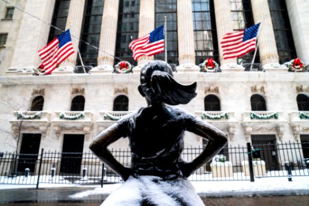 Snow covered Fearless Girl and three American Flags